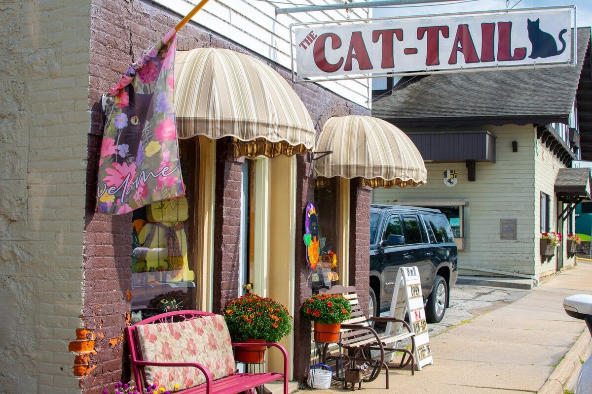FC Business fronts-5 Cozy storefront of The Cat-Tails boutique with striped awnings, colorful flowers, and outdoor seating in Buffalo County, Wisconsin.